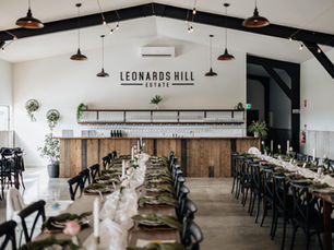 A wedding venue with a custom bar, table and chairs with stylish tableware.