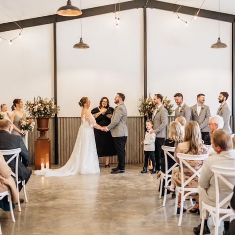 A couple getting married by a celebrant inside a premium venue with their wedding party by their side and guests watching.