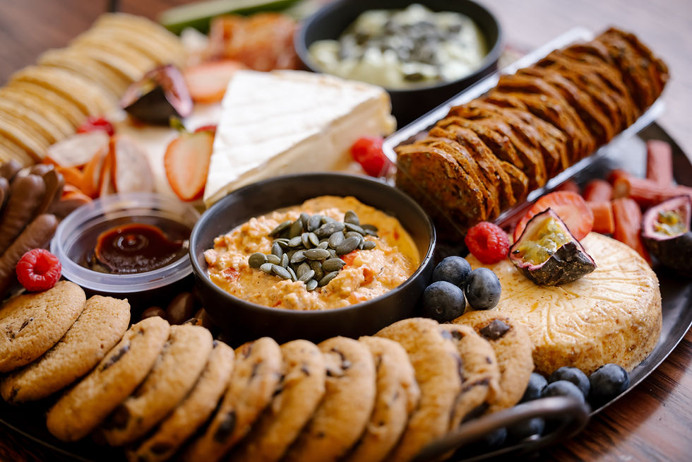 Assorted cookies, cheese, fruit and dips arranged on a platter, with blueberries and raspberries on a wooden table.