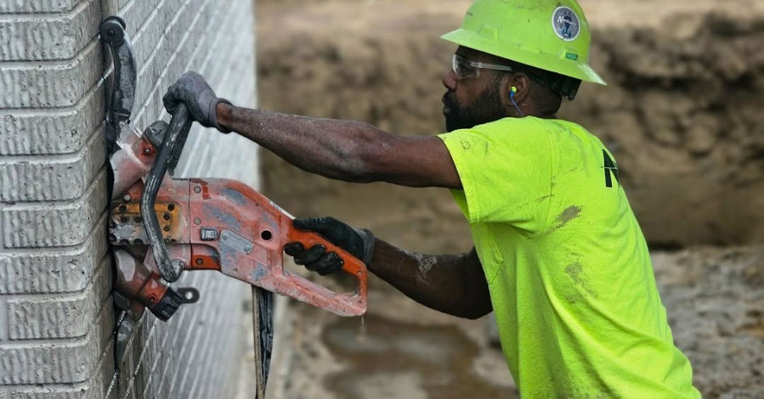 Man hand sawing opening into foundation