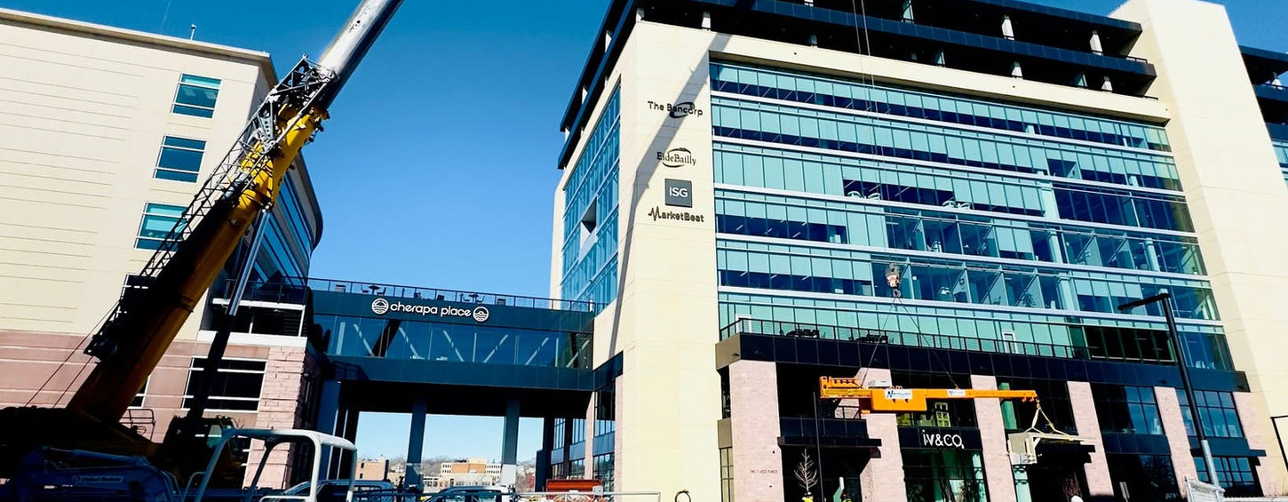 Crane lifting in front of building walkway