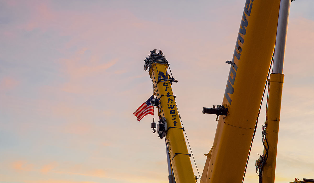 Crane boom in air during golden hour with United States flag