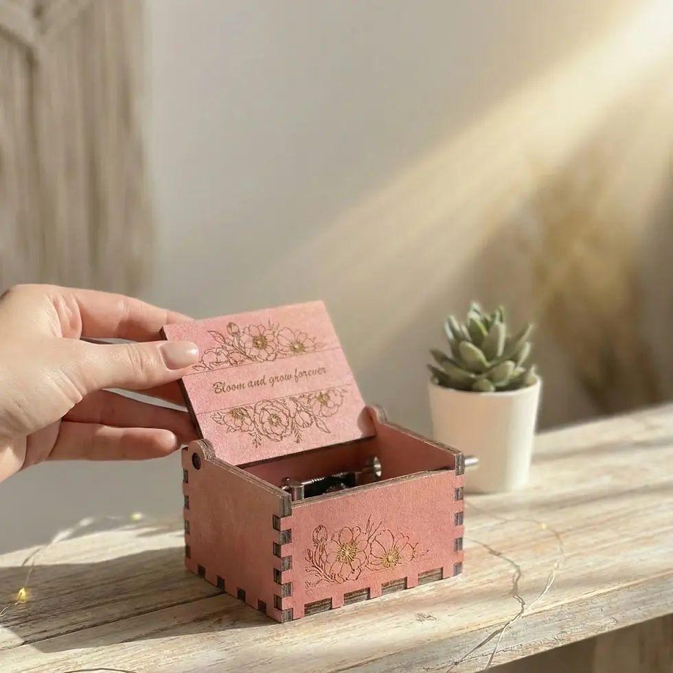 Close-up of a person's hand playing a floral-themed music box on a bright shelf.