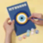 Close-up painting of a blue eye design on a Mykonos paint by numbers canvas using a fine-tip brush and acrylic paints.