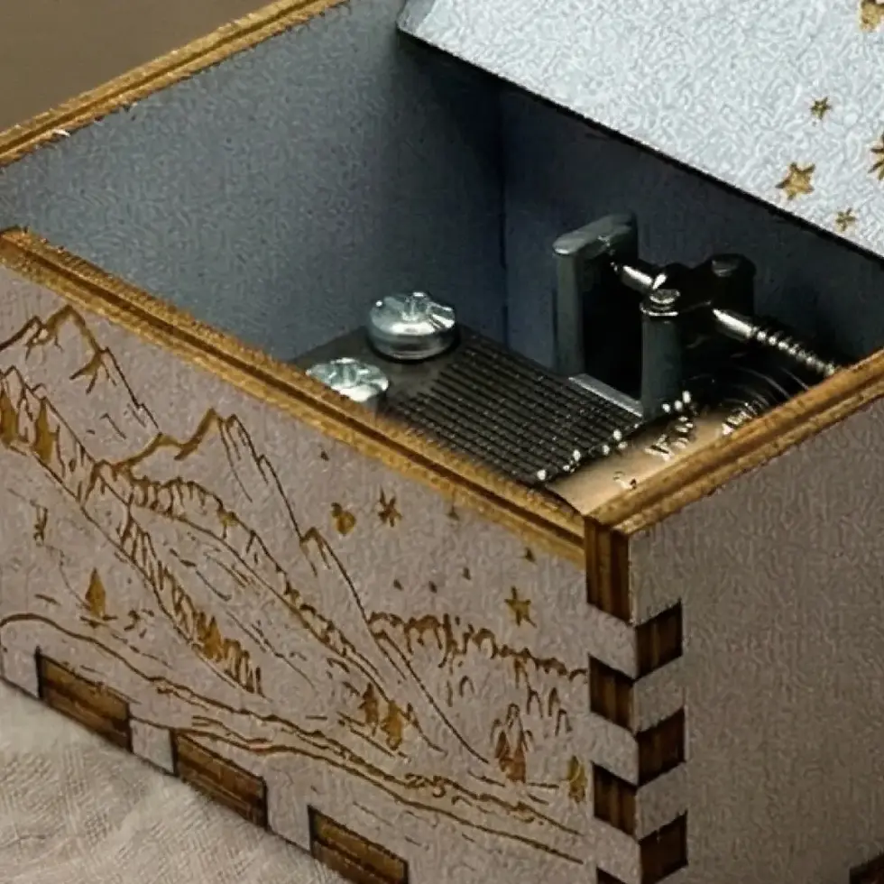 Thumbnail: Detailed view of the lid of a starry night themed wooden music box with star and mountain carvings.