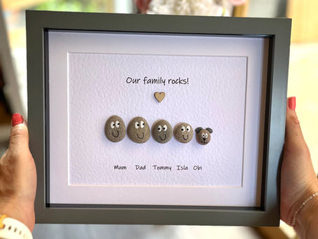 A selection of pebbles depicting a family placed within a picture frame to create a family gift