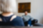 Über die Schulter einer Klientin sieht man den freundlich lächelnden Psychotherapeuten M.Merkler in der psychotherapeutischen Praxis in Trier.