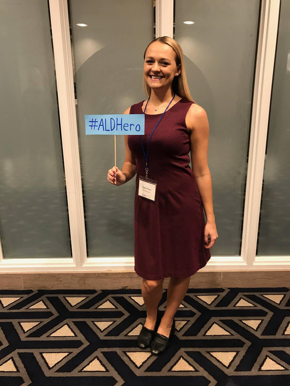 Taylor smiling wearing red dress holding #ALDHero sign