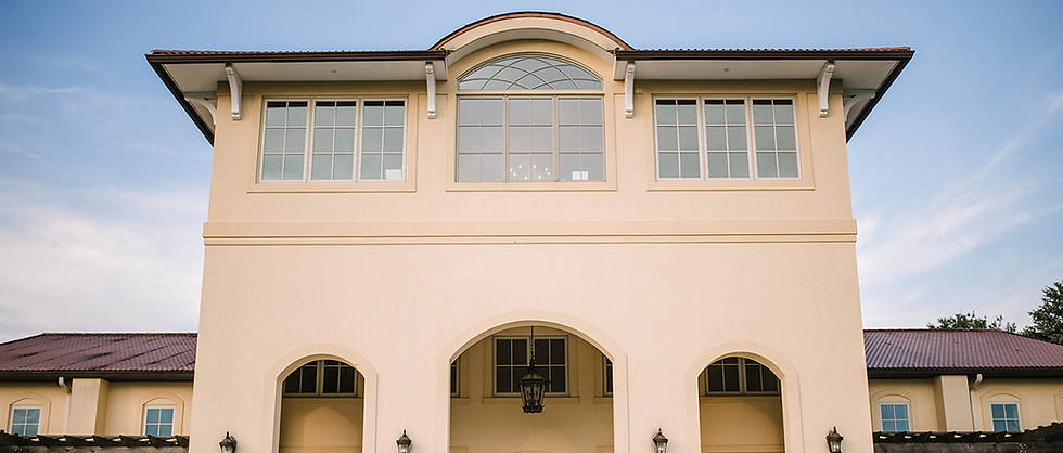 The front of Breaux Vineyard in Purcellville, Virginia which is a tan stucco building in a New Orleans architecture style.