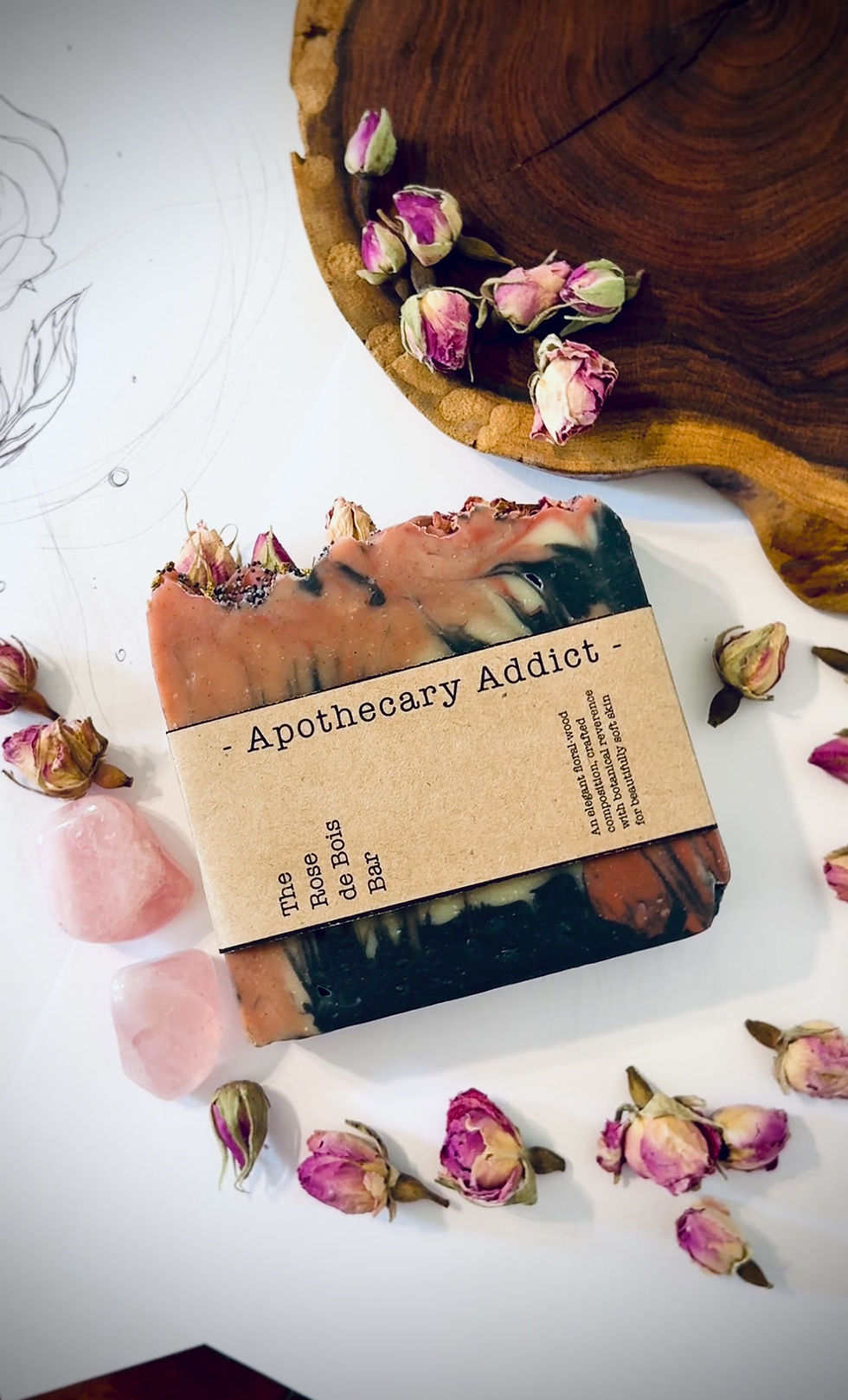 Thumbnail: Rose de Bois Premium Soap Bar displayed amongst rose quartz tumbles, rose buds, and wood piece to evoke rose-wood scent