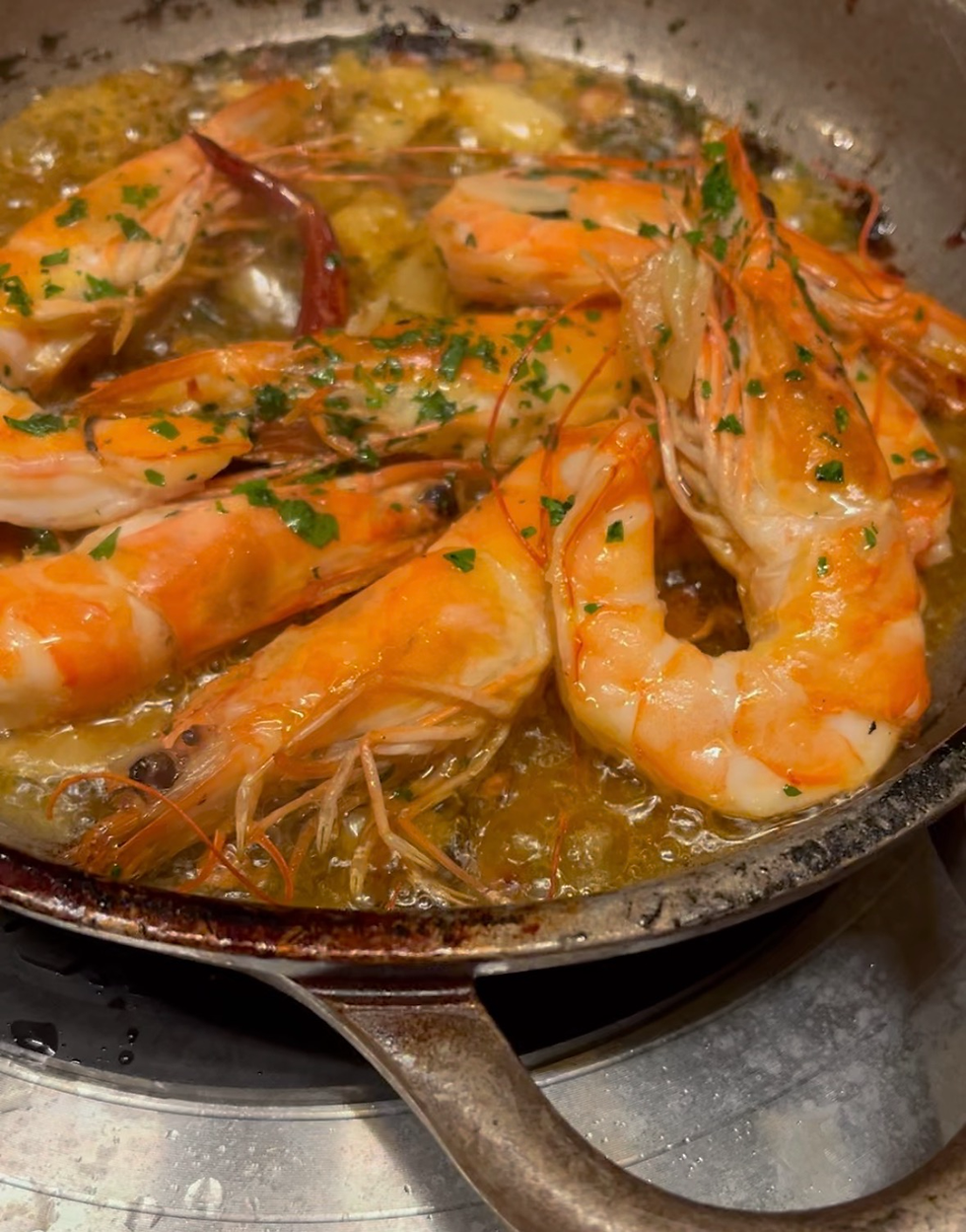 Gambas al ajillo - shrimp in a sizzling pool of extra virgin olive oil infused with sliced garlic and guindilla peppers topped with a sherry sauce.