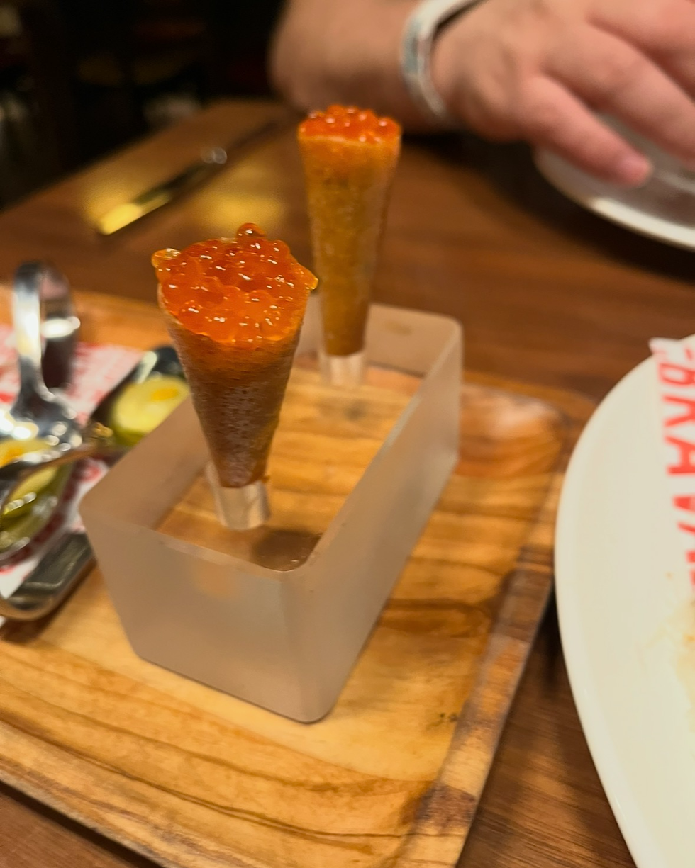 Cono de Salmón Crudo con Huevas de Trucha - a small, crispy cone made of brik pastry filled with salmon tartare and topped with trout roe.