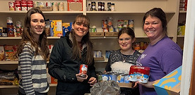 Youth group members and sponsors restocking the food pantry