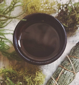 Small-batch herbal body oil being crafted in the Feral Hollow clinical apothecary, highlighting handmade botanical wellness products.