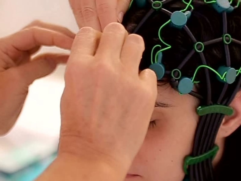 A clinician fitting an EEG cap on a child for a qEEG brain map
