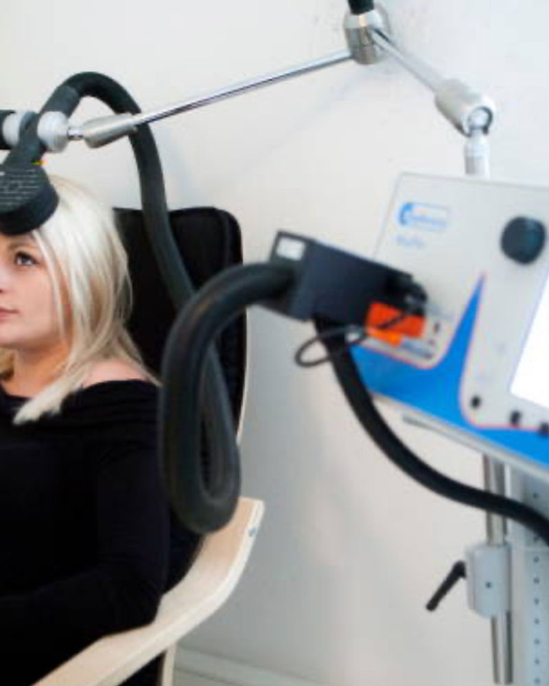 A patient seated in a treatment chair during a brain stimulation session