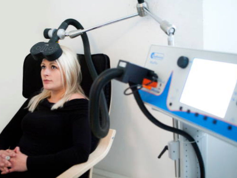 A patient seated in a treatment chair during a brain stimulation session