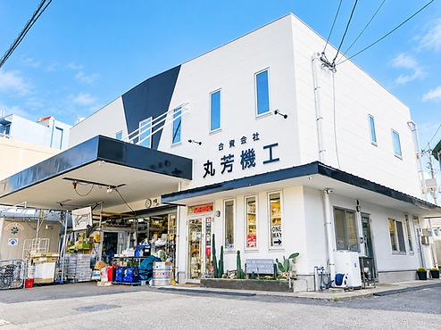 青空に映える丸芳機工の店舗ファサード.png