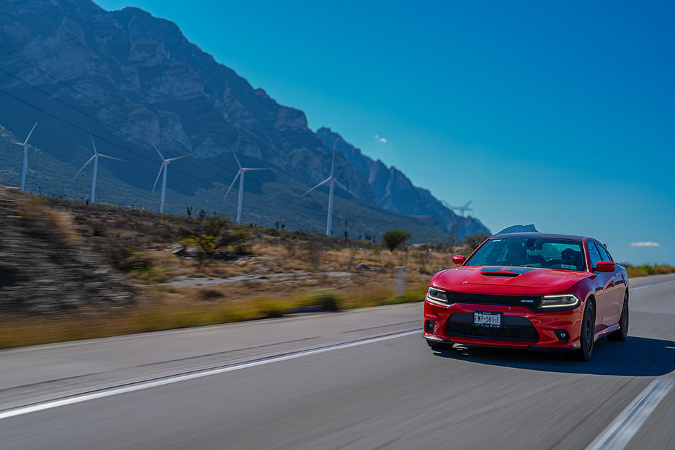 Coche rojo en carretera con molinos y montañas