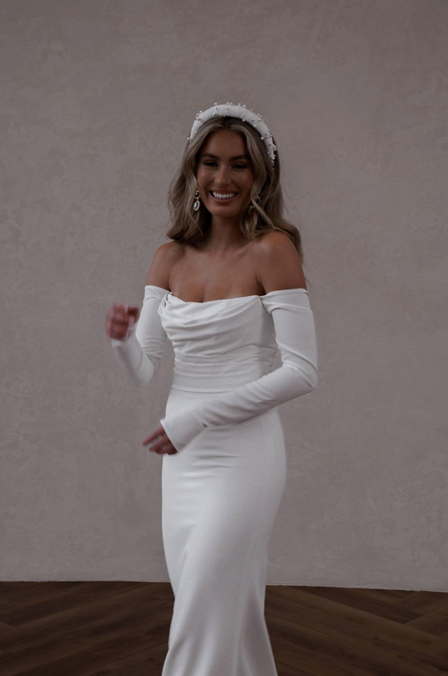 Bride wearing white crepe wedding dress with fitted long sleeves that are detachable