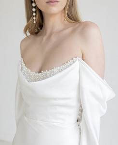 White silk wedding dress with a pointed strapless neckline and pearls