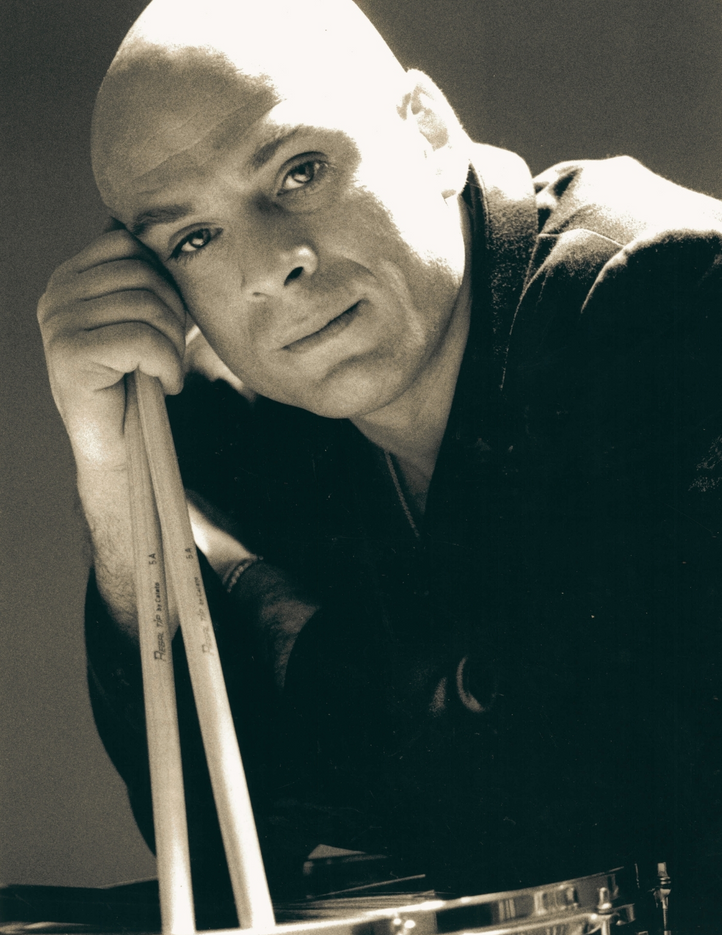 Armando Bertozzi, batterista jazz, ritratto in primo piano in toni seppia mentre tiene in mano le bacchette.