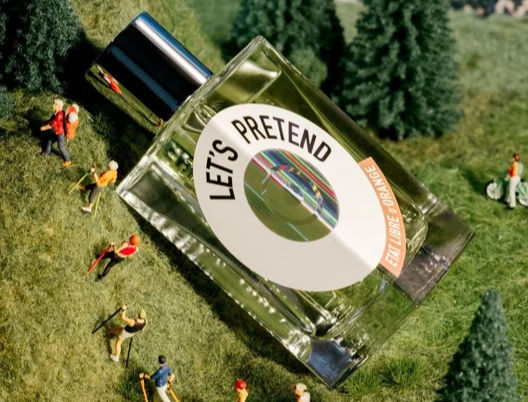 Flacone di profumo "Let's Pretend" di Etat Libre d'Orange adagiato su un paesaggio in miniatura con
