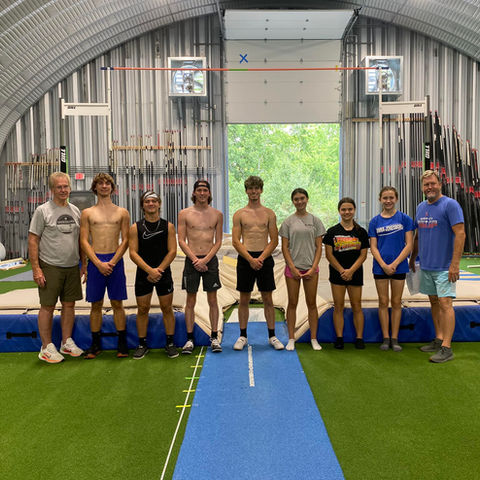 Group of pole vaulters standing together at River City Vault Club's indoor facility.