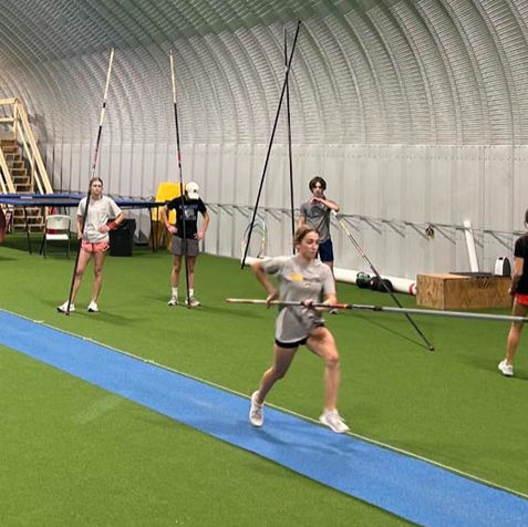 Pole vaulter running indoors down the runway while carrying the pole