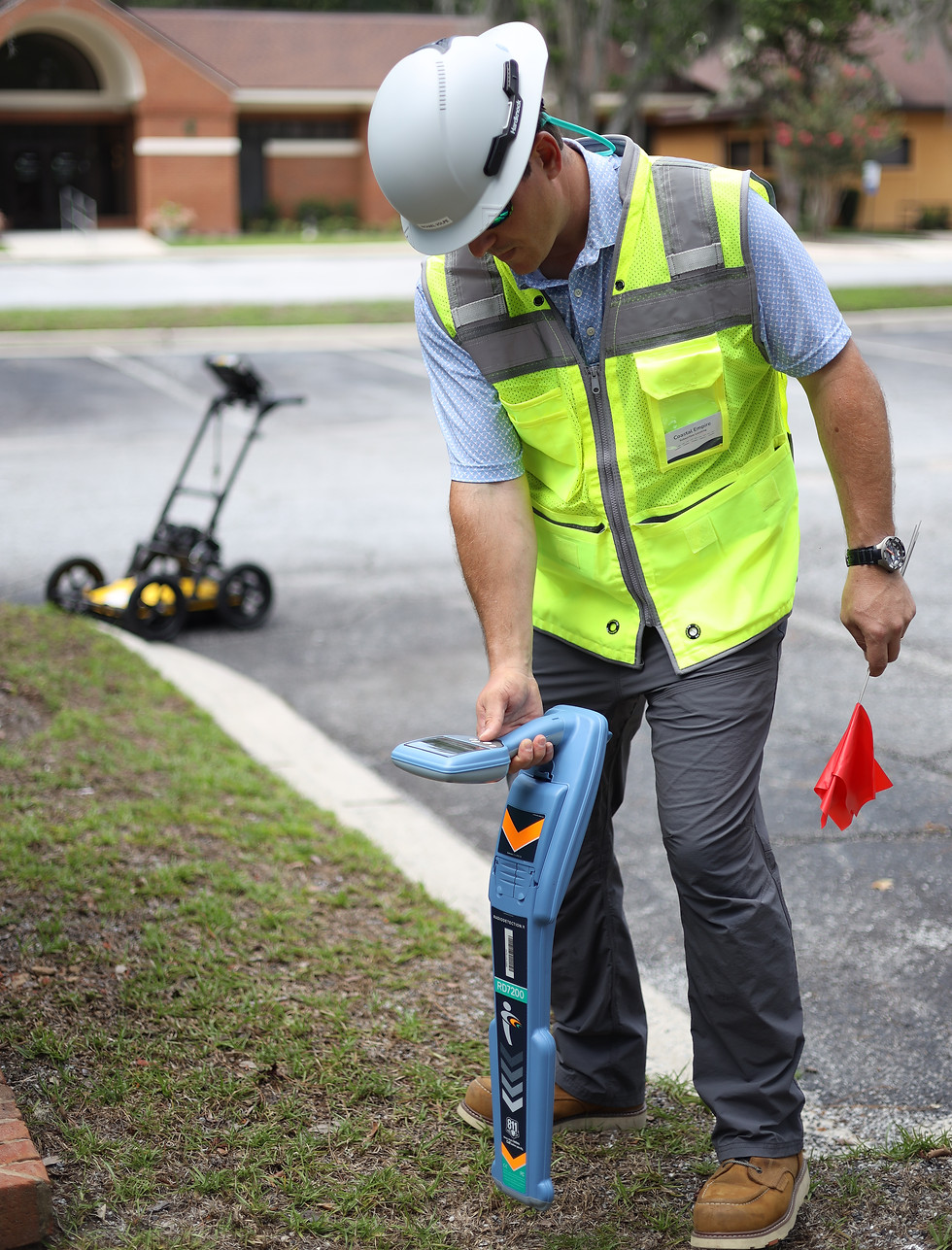 Michael demonstrating the use of electromagnetic locating along with GPR device in background