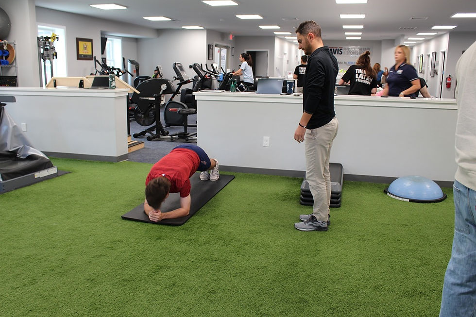 Athlete performing a plank on a training mat while a coach observes, demonstrating core strengthening as part of correcting hidden muscular imbalances.