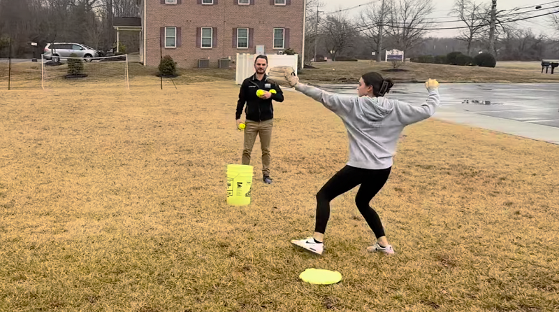 Softball pitcher practicing outdoors demonstrating mechanics linked to pitching shoulder pain from workload fatigue