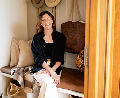 Shelley Kennedy, pelvic flood physiotherapist, a dark haired woman sitting comfortably in her home as she smiles at the camera