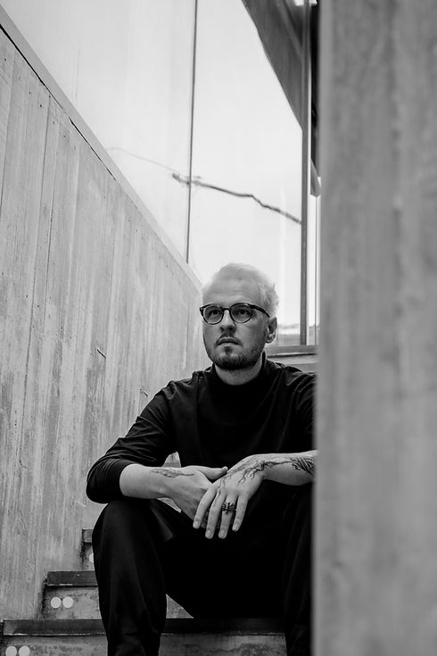 foto de Allan Casagrande sentado na escadaria lateral do edifício Pietro Bo Bardi, novo prédio do MASP, em São Paulo. ele olha para a frente, de forma contemplativa, como se pensasse sobre o futuro