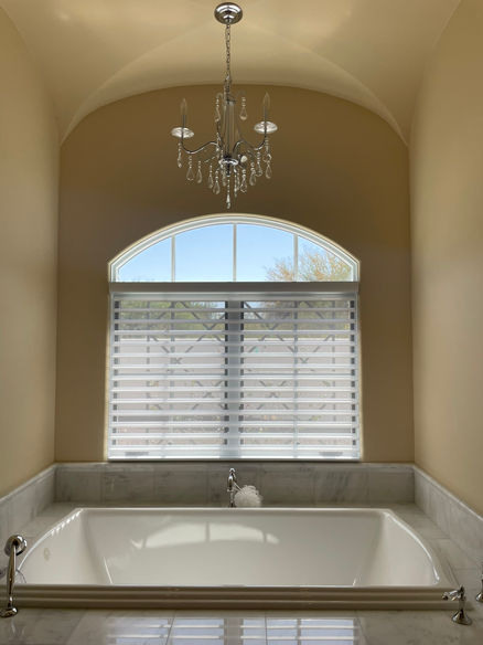 Arch window in a bathroom with a shutter window treatment