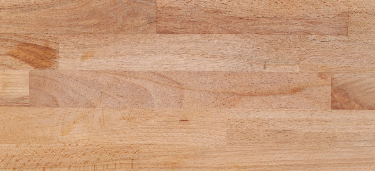 Gros plan sur un parquet stratifié en bois clair, montrant la texture lisse et uniforme du revêtement, idéal pour un sol moderne et résistant.