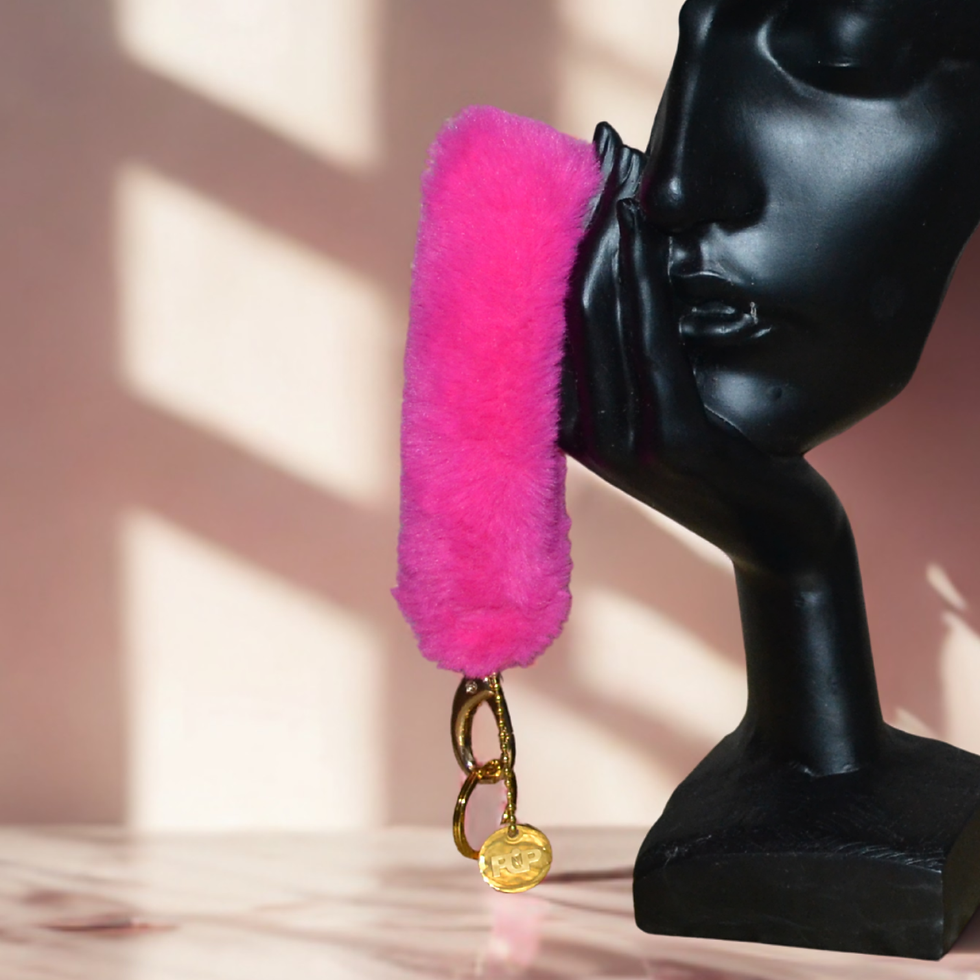 Bracelet téléphone en fausse fourrure rose vif accroché à une sculpture