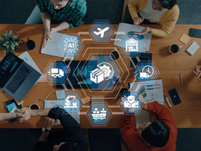 Overhead view of a diverse project team collaborating at a table with laptops and documents, overlaid with connected hexagon icons representing AI, air freight, warehousing, delivery trucks, shipping, robotics, and supply chain security, illustrating integrated logistics planning.