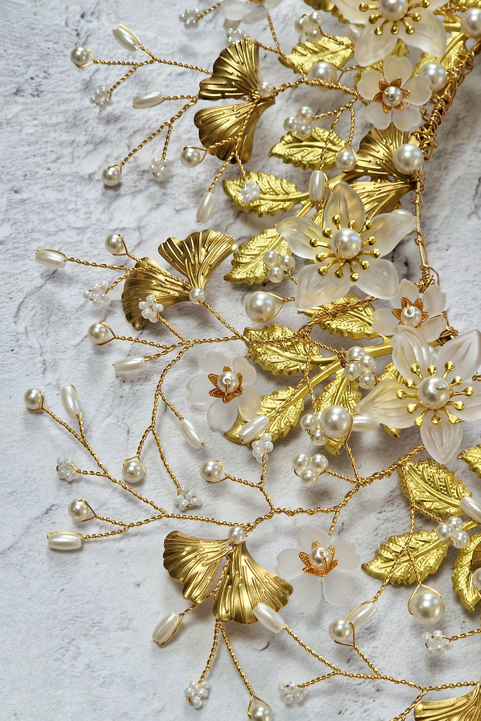 Thumbnail: Close-up of gold tone ginkgo and rose leaves, white matte flowers, and Preciosa crystal pearls in an organic arrangement