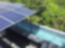 Paneles solares sobre piscina cuadrada en azotea. Fondo de árboles verdes, luz solar refleja en el agua azul, ambiente sereno.