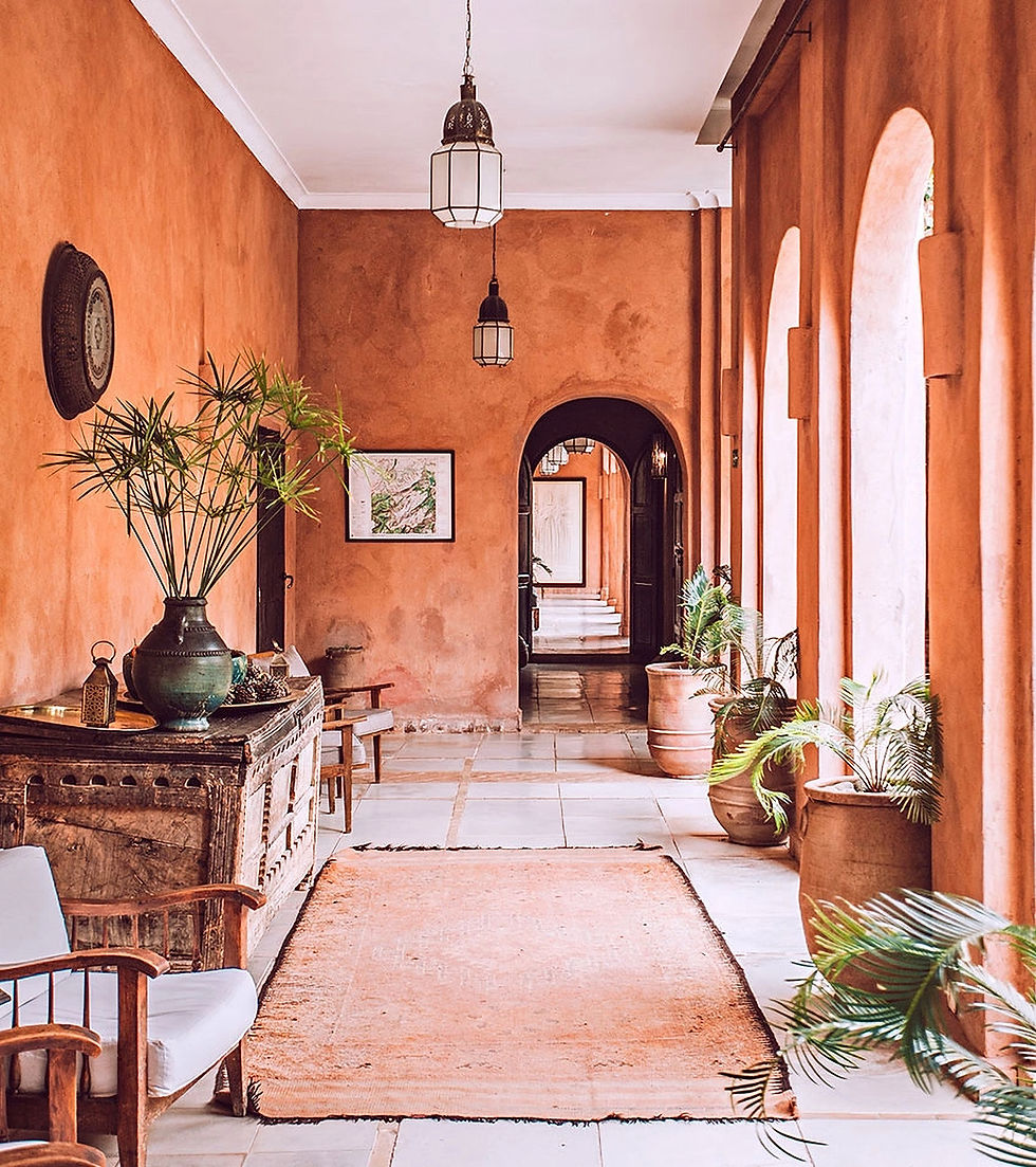 Warm terracotta hallway with hanging lanterns, potted palms, arched openings, and a long rug in a calm, elegant interior