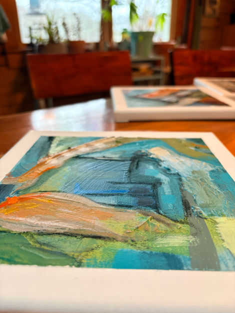 oblique view of bright, textured abstract painting in colors of orange, yellow, red, aqua, green, gray, and black