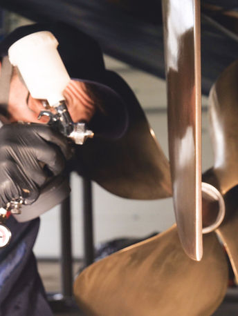 picture of a gold propeller and a man spraying it was a paint gun