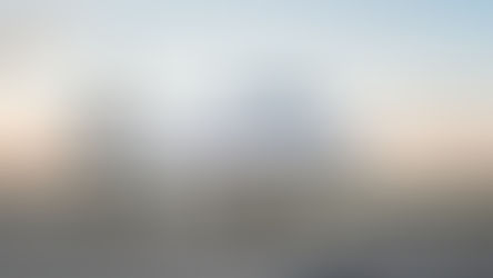 Side-front view of a white business jet on the tarmac at sunset, showing engines and landing gear, with open landscape, soft sky and IONA JETS branding in the corner.