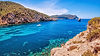 A private yacht anchored in a secluded, turquoise cove in Ibiza, a stunning destination for a private jet charter to and from Ibiza.