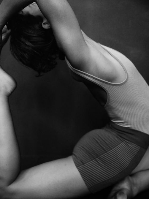Black seamless ribbed bodysuit with a deep scoop neckline, high-cut leg, and subtle contrast stripe down the center front. Crafted from a breathable blend of RWS-certified merino wool and recycled polyester, it offers gentle compression, a soft second-skin feel, and all-day comfort for movement or everyday wear.
