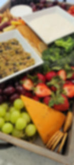 Close up of a charcuiterie platter with wedge of gourmet cheese, spinach dip, grapes, berries and crackers..