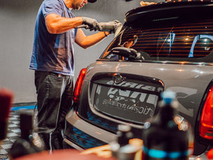 Profissional da BIRDS Estética Automotiva realizando polimento automotivo em carro dentro de ambiente profissional, com máquinas, boinas e ferramentas de polimento visíveis.