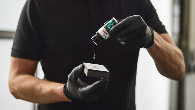 Profissional pingando o coating no aplicador durante o processo de aplicação.