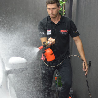 Profissional realizando a lavagem de um carro com Shampoo SONAX, aplicando o produto com técnica adequada para limpeza segura e acabamento premium.